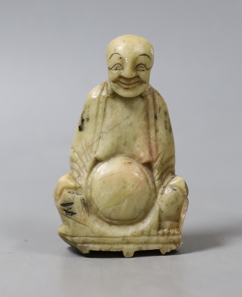 A carved soapstone figure of a seated smiling Buddha - 8cm tall